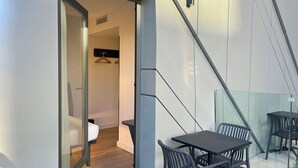 Un intérieur moderne avec une cloison en verre, une table avec des chaises et un porte-manteau suspendu.