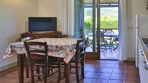 A dining area with a table and chairs, a television, and a sliding glass door leading to an outdoor patio. - Perone, two-room apartment in a villa in Marina di Campo, with equipped garden, covered parking spac (Campo nell'Elba)