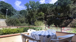 A balcony with a table and chairs, overlooking a scenic hillside with trees and a road. - FETOVAIA1 - FETOVAIA 1 (Campo nell'Elba)
