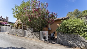 A residential street with a stone wall, a parked scooter, and a house with a tiled roof. - FETOVAIA1 - FETOVAIA 1 (Campo nell'Elba)