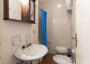 Un baño con lavamanos, inodoro y cortina de ducha.
