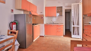 A compact kitchen with orange cabinets, a stainless steel refrigerator, a gas stove, and a sink. - FETOVAIA1 - FETOVAIA 1 (Campo nell'Elba)