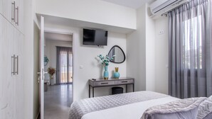 A hotel room with a bed, a desk with a mirror, a TV, and a window with curtains. - Luxury Katsoulakis Apartments (Alikianos)