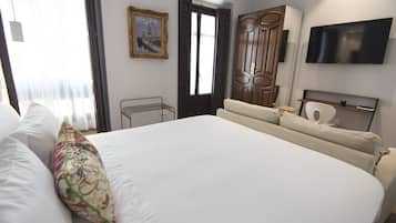 Habitación de hotel con una cama grande, un televisor montado en la pared y una puerta que da a otra habitación.