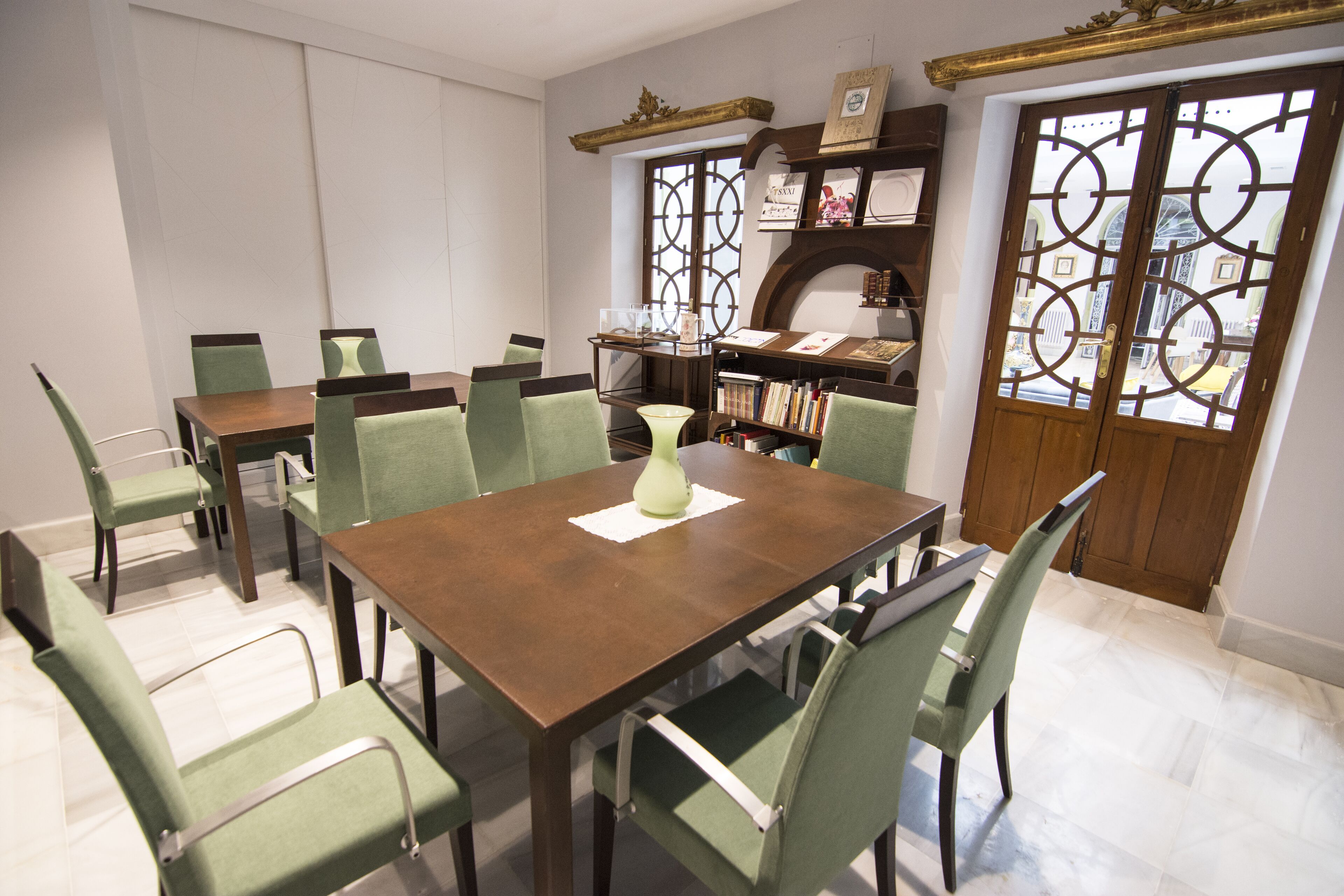 A dining area with a wooden table and green upholstered chairs.