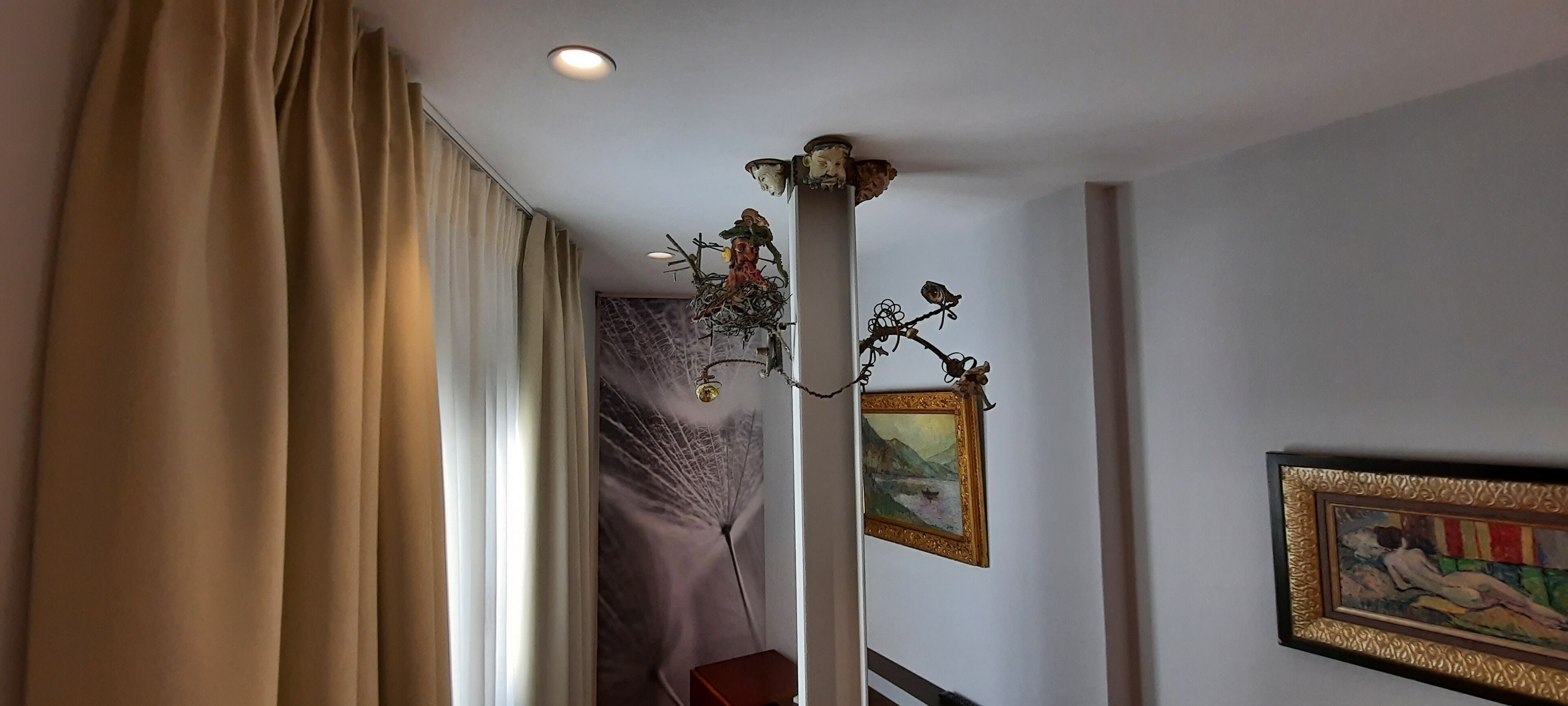 Una habitación de hotel con cama, candelabro y obras de arte en las paredes.