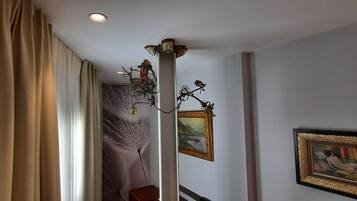 Una habitación de hotel con cama, candelabro y obras de arte en las paredes.