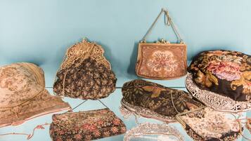 A collection of vintage-style handbags and hats displayed against a light blue background.