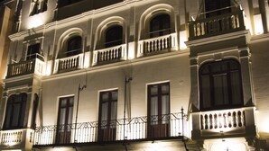 A historic building with multiple balconies and arched windows, illuminated at night. - Hotel Oleum (Andujar)