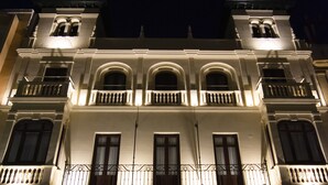 A building with a symmetrical facade, multiple balconies with wrought iron railings, and evenly spaced windows. - Hotel Oleum (Andujar)
