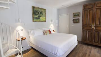 Un dormitorio con una cama, un armario de madera, una escalera blanca y un cuadro en la pared.