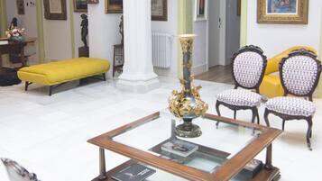 A spacious living room with a glass coffee table, a yellow sofa, and patterned chairs.