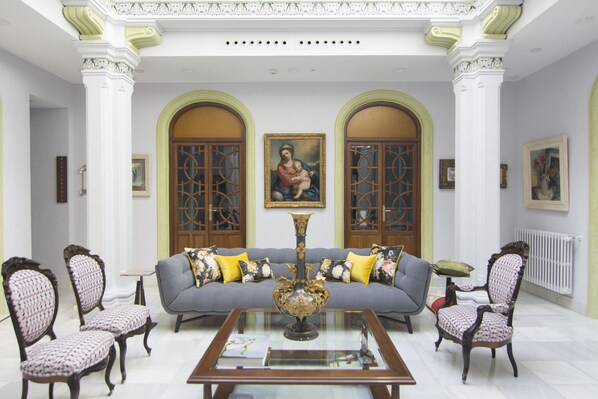 Un salón amplio con un sofá gris, dos sillones, una mesa de centro y un gran jarrón decorativo.