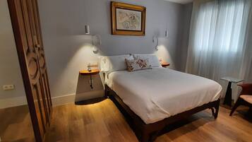 A bedroom with a wooden bed, bedside tables, a chair, and a painting on the wall.