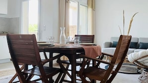 A dining area with a wooden table and chairs, a vase, and a view of the living room.