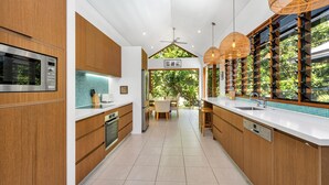 Una cocina moderna con armarios de madera, un microondas integrado y un amplio ventanal con vistas a zonas verdes.