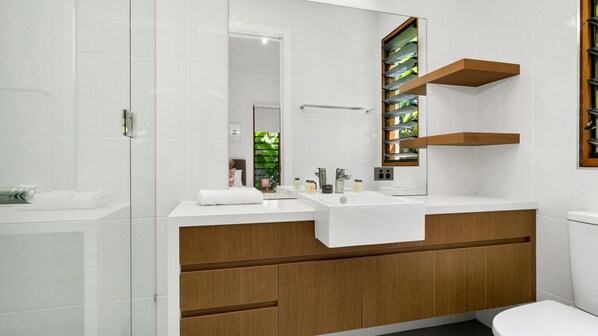 A modern bathroom with two sinks, a large mirror, and wooden cabinetry.