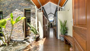 Un pasillo con pared de piedra, piso de madera y plantas en macetas.