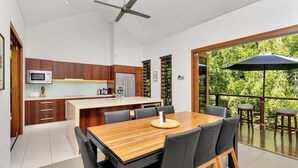 Una cocina moderna con armarios de madera, una isla central y un comedor con una mesa grande y sillas.