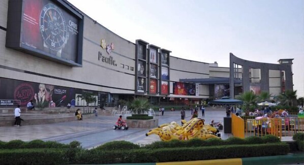 A shopping mall with a large outdoor area, a fountain, and a yellow inflatable structure. - Hotel Olive Saffron (New Delhi)