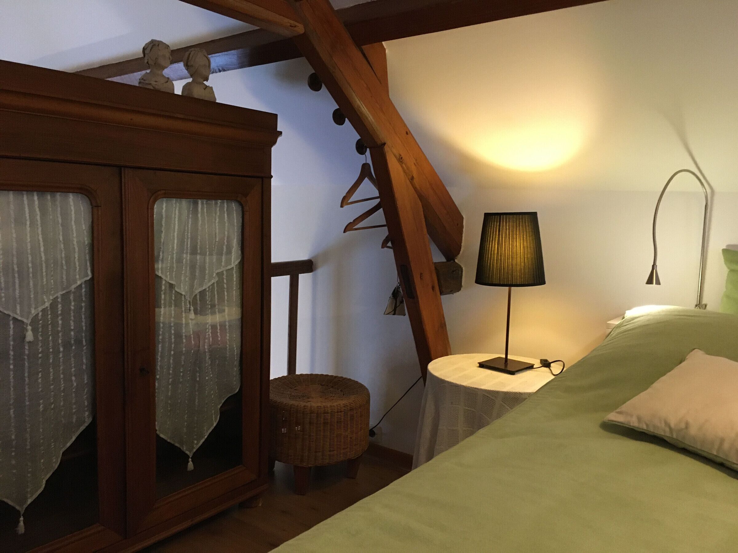 Une chambre à coucher avec un lit, une armoire en bois, une lampe et une petite table.