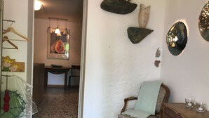 Ein Zimmer mit einem Holzbett, einem Tisch mit Gläsern und Wanddekorationen, darunter eine Fruchtscheibe und abstrakte Formen.
