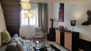 Ein gemütliches Wohnzimmer mit Sofa, Glastisch, Kamin und einem Fenster mit Vorhängen.