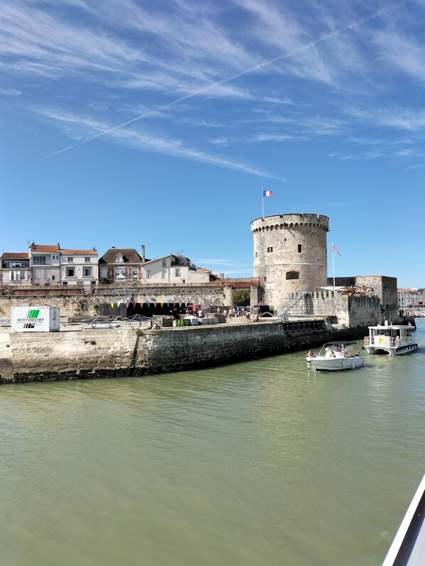 A historic tower with a flag, a waterfront promenade, and a row of buildings. - Room 12 m plus private shower room 4 m plus balcony 5 m'a 800 metres ocean (La Rochelle)