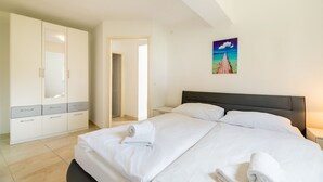 A hotel room with a bed, a wardrobe, a painting, and a door leading to another room. - 100 metres to the crystal clear Adriatic Sea (Baska)