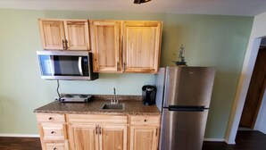 A kitchen with wooden cabinets, a microwave, a toaster, a sink, and a refrigerator. - {Forget-Me-Not Inn} Alaskan Waterfront Vacation Rental (Eagle Suite) (Sitka)