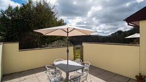 Een terras met een tafel, stoelen, een parasol en een plant in een pot.