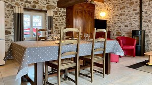 A dining area with a wooden table set for four, surrounded by stone walls and a rustic wooden ceiling.