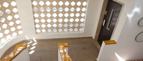 Una escalera con barandilla beige y amarilla que da a un rellano.