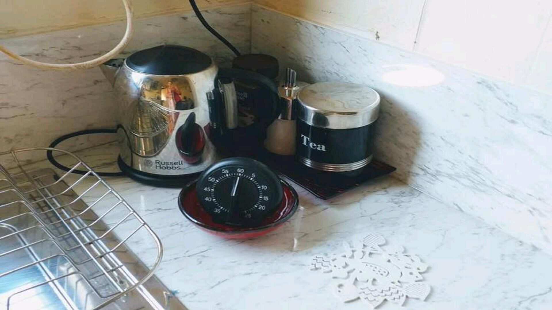 A kitchen with a Russell Hobbs coffee maker, a tea container, a timer, and a metal rack.