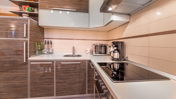 Une cuisine moderne dotée d’un îlot central, d’appareils électroménagers en acier inoxydable et d’un four à micro-ondes.