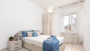 Une chambre à coucher avec un lit, une table de chevet, une lampe et une fenêtre avec des rideaux.