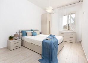 A bedroom with a bed, bedside table, lamp, and a window with curtains.