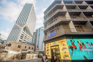 A modern building with a unique angular design, a prominent bank sign, and a colorful restaurant advertisement. - The Seven Apartments (St. Julian's)