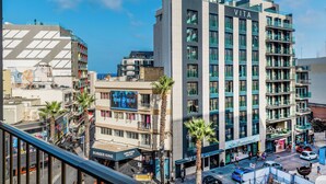 A modern hotel with multiple floors, a prominent 'VITA' sign, and a view of the street below. - The Seven Apartments (St. Julian's)