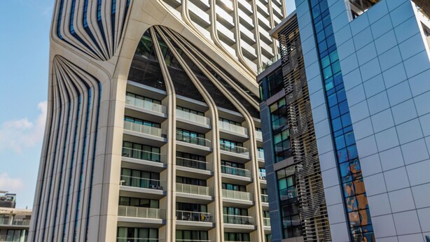 A modern high-rise building with a unique architectural design, featuring a curved facade and multiple balconies. - The Seven Apartments (St. Julian's)