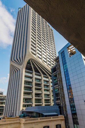 A modern high-rise building with a unique architectural design, featuring a curved facade and multiple balconies. - The Seven Apartments (St. Julian's)