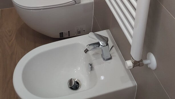 Ein Badezimmer mit Toilette, Waschbecken und einem weißen Heizkörper.