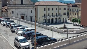 A parking area with several cars, a blue van, and a building with a cross on top. - Little paradise Suite in the center of Castel di Sangro (Castel di Sangro)