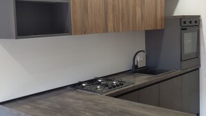 Eine moderne Küche mit einer zentralen Kochinsel, eingebauten Schränken und einem Backofen für zwei Auflaufformen.