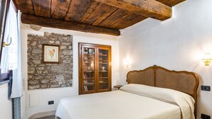 Un dormitorio con pared de piedra, puerta de madera y cama con cabecera.
