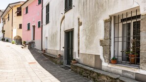 Una calle estrecha con edificios de fachadas de piedra y contraventanas.