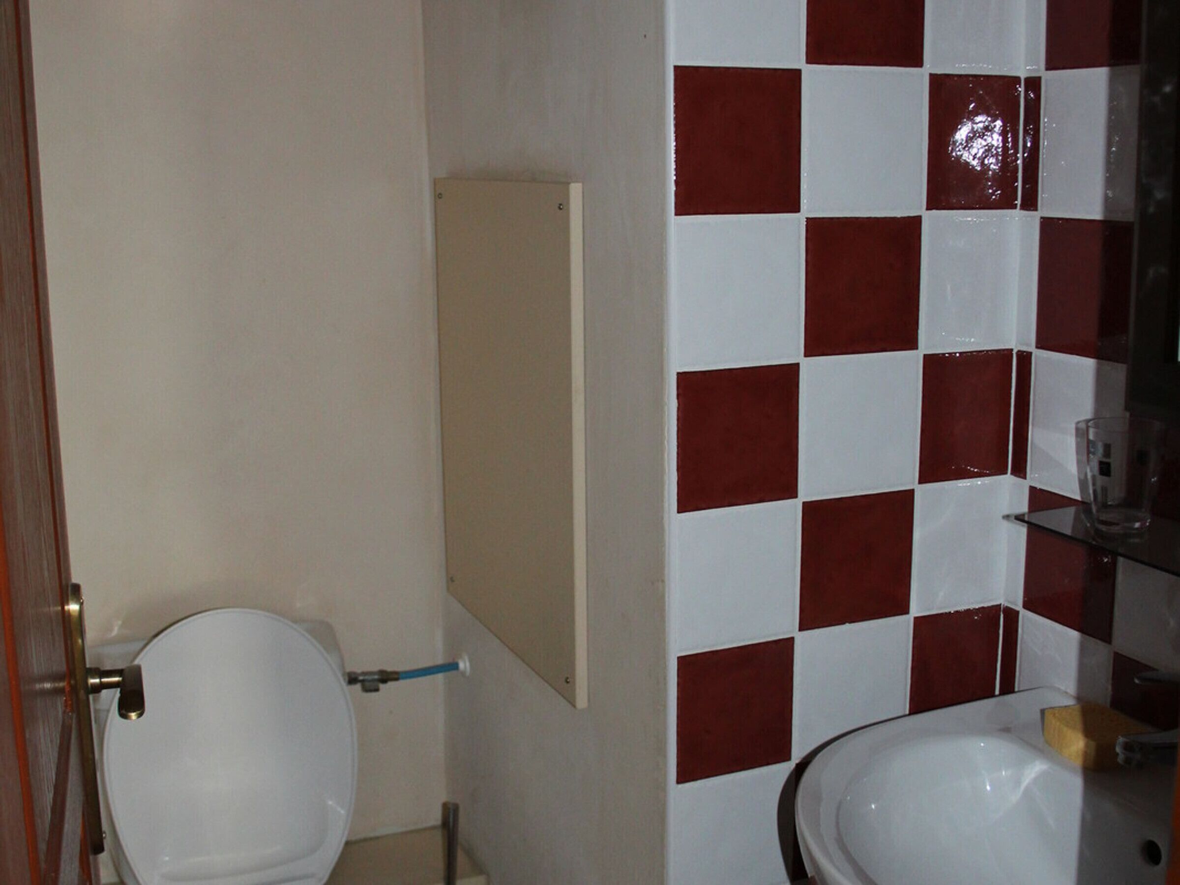Een badkamer met toilet, wastafel en spiegel.