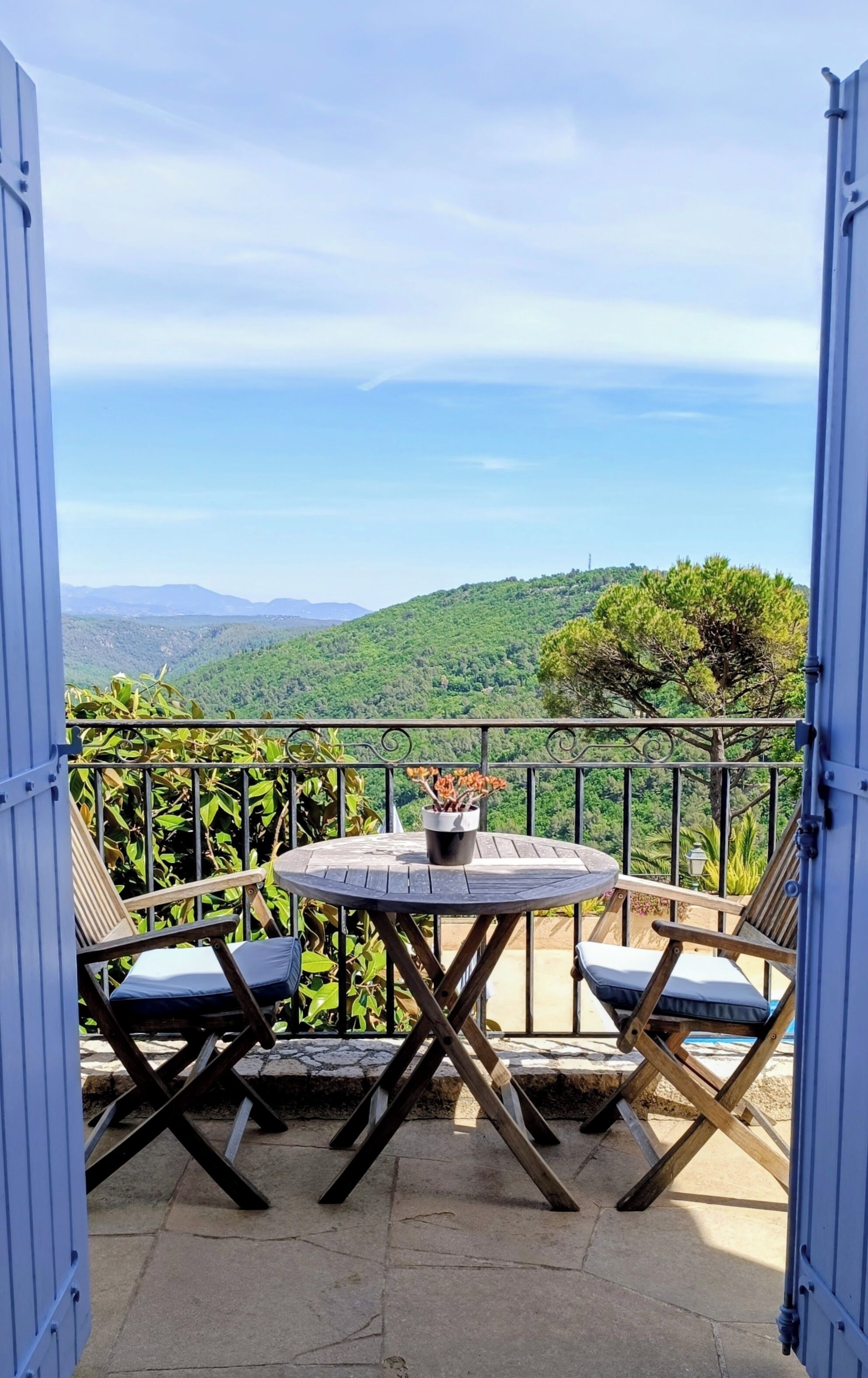 Un espace extérieur aménagé avec une table et deux chaises, offrant une vue sur un paysage montagneux.