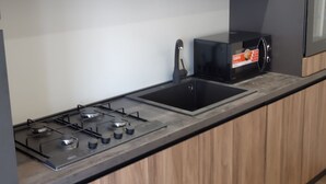 A modern kitchen with a gas stove, black cabinets, and a built-in oven. - Little paradise in the heart of Castel di Sangro (Castel di Sangro)
