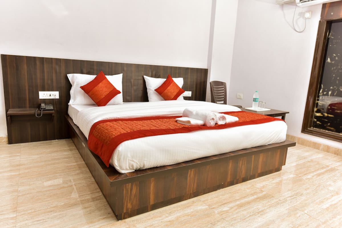 A modern hotel room with a large bed, wooden headboard, and a view of the city.
